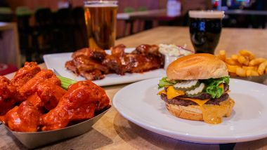 Buffalo style wings, with cheeseburger, ribs and 2 drinks on display at a table inside The SPortsbook at Hollywood Casino at Greektown