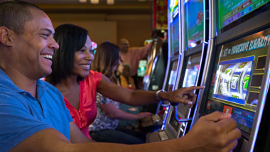 man and woman smiling playing a slot machine