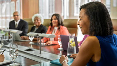 looking over the shoulder of a woman to see the rest of the meeting attendees